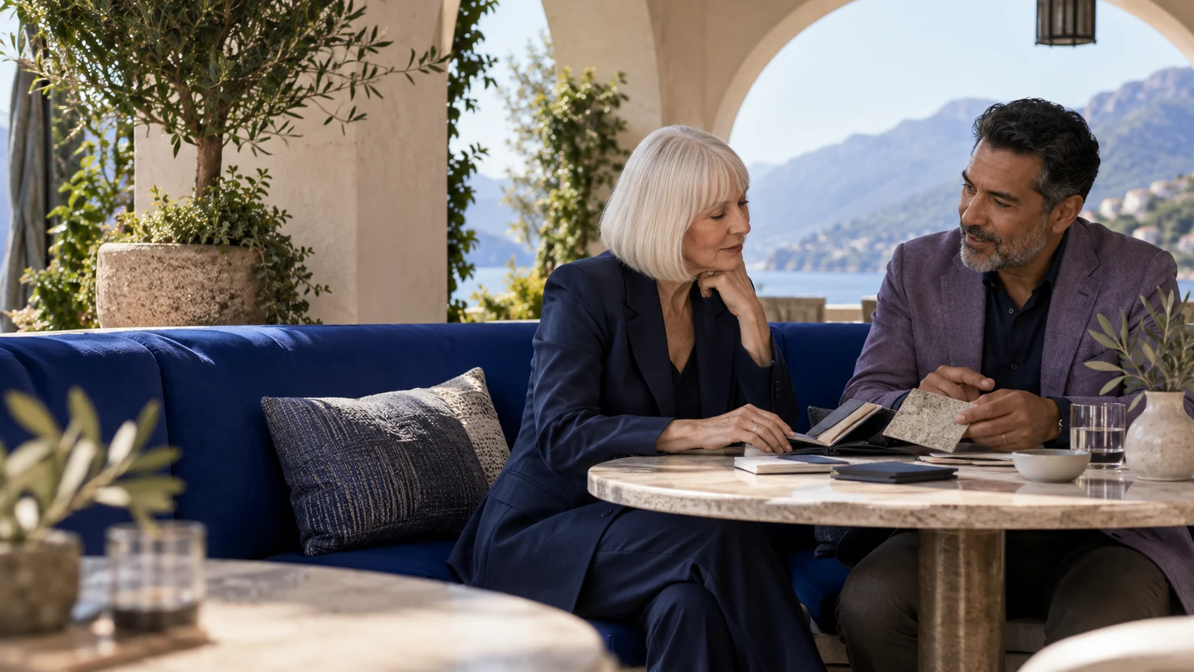 Two professionals reviewing material samples on a sheltered restaurant terrace.